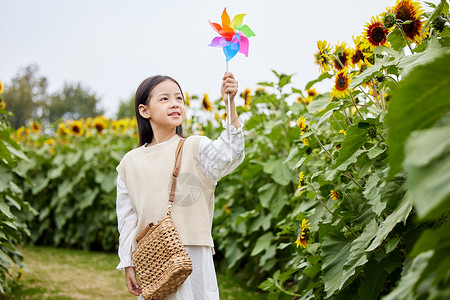 向日葵花田里玩耍的小女孩背景图片