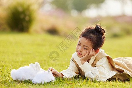 大象与兔子可爱女孩在草地上与兔子玩耍背景