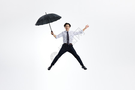 跳跃的白领男性撑雨伞背景图片