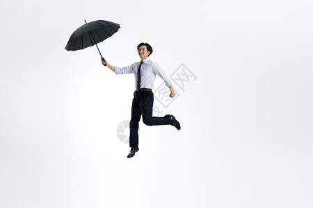 跳跃的白领男性手拿雨伞图片