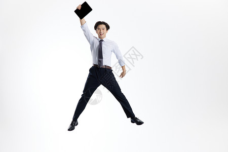 跳跃的商务青年男士手拿平板电脑图片