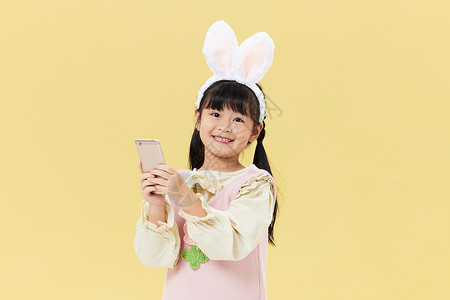 头戴兔耳朵的小女孩玩手机背景图片