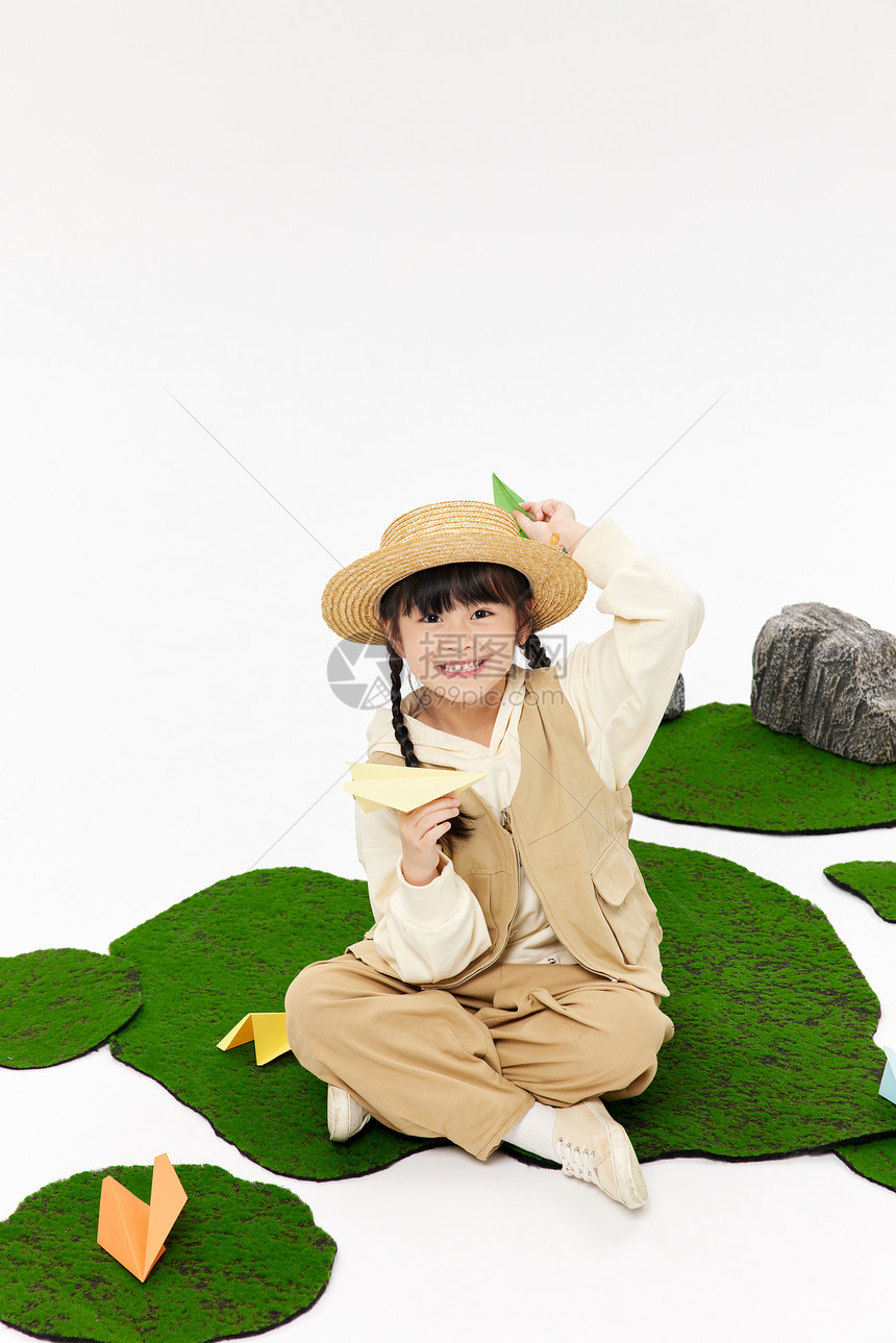 小女孩草地上玩纸飞机图片