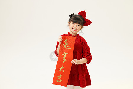 红色标题条幅身穿红衣服的小女孩双手拿春联背景