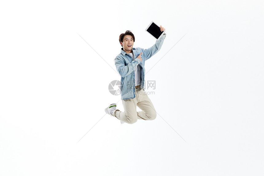 跳跃的青年男性展示平板电脑图片