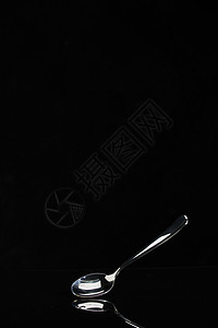 黑色背景上的不锈钢勺子背景图片