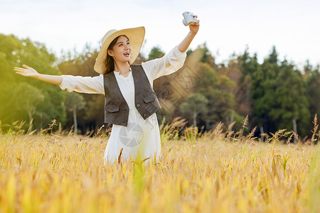 美女站在稻田里使用相机自拍图片