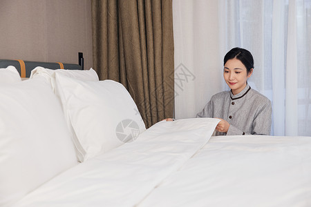 酒店服务保洁员整理客房床铺背景图片
