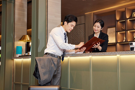 酒店前台服务员为顾客办理入住手续酒店服务高清图片素材
