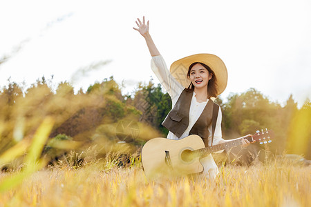 秋季稻田美女手拿吉他高清图片