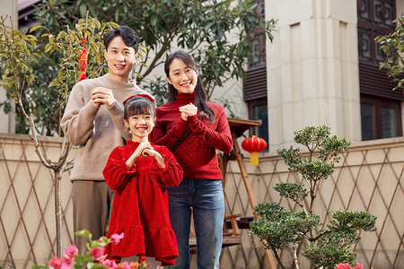 过年欢聚一家三口在院子里拜新年背景