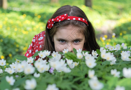 小女孩坐在树林里的花丛中图片