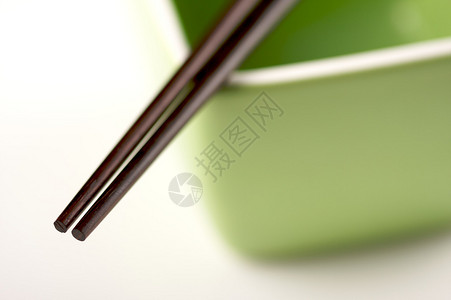 白色背景上的筷子和绿色碗图片