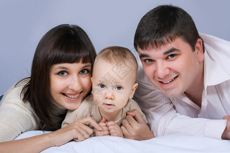 家庭幸福的家父亲母亲和婴儿男孩躺图片