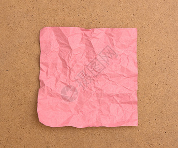 棕色板上隔离的皱巴的粉红色便条纸图片
