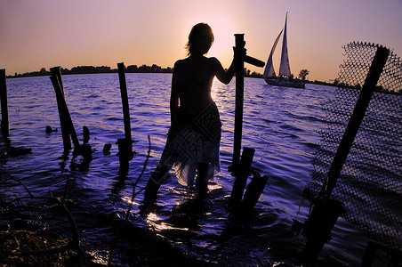 在日落和水背景的女剪影图片