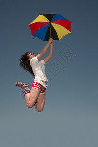打着彩色伞的女孩高地往上跳图片