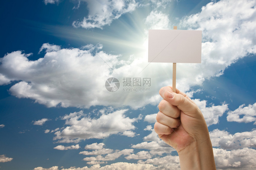 男人拿着空白标志在戏剧云彩和蓝天与太阳光芒准备好您自己的信息图片