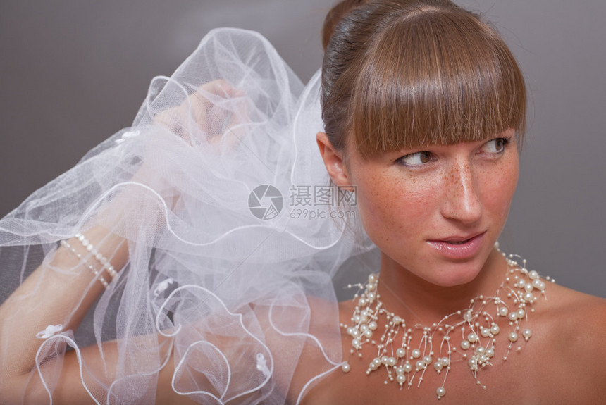 灰色背景下戴面纱的美丽新娘的肖像图片