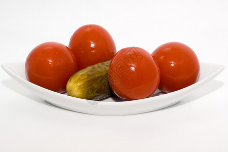 白色背景盘子上的自制咸番茄和黄瓜图片
