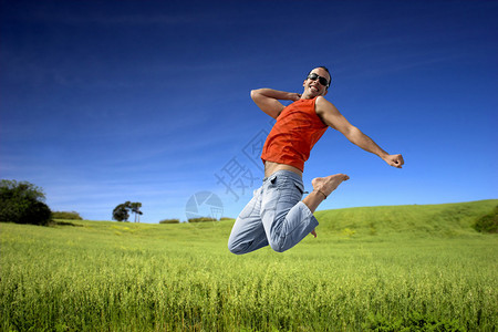 男子在绿草地上跳跃天空美丽多云图片