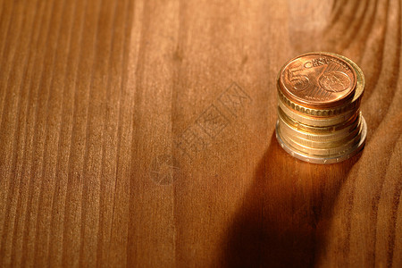 将欧元硬币堆放在木制背景上背景图片