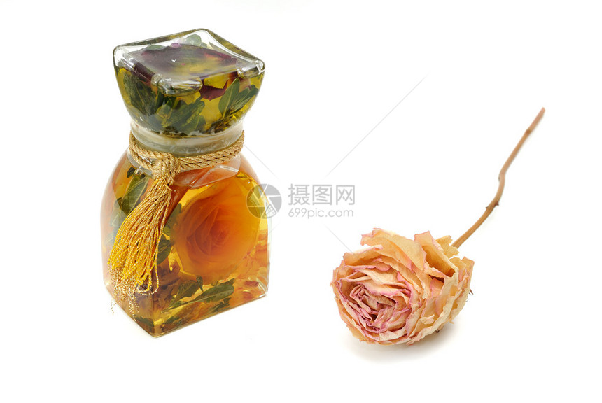 浴油和发酵玫瑰花在玻璃瓶里隔着白色图片