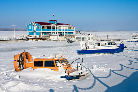 在结冰的河岸的气垫船反对蓝天图片