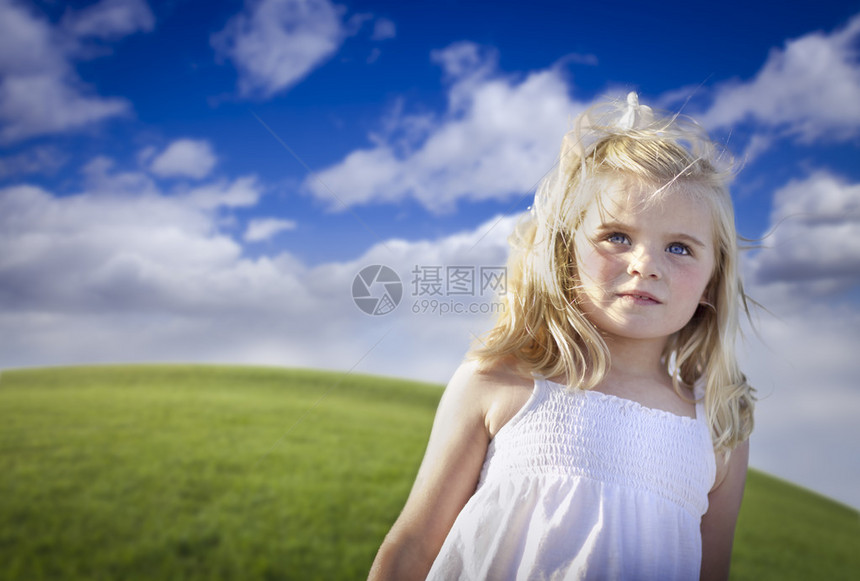 可爱的蓝眼睛女孩在外面的草地上玩耍图片