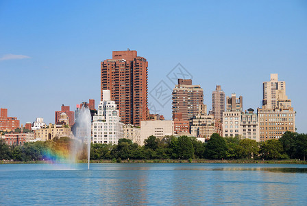 纽约中央公园喷泉与彩虹和城市曼哈顿天际线与摩天大楼和树木湖反射图片