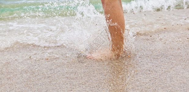 男孩在沙滩上跳入水中的脚图片