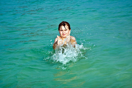 年轻快乐的棕发男孩喜欢游泳和跳图片