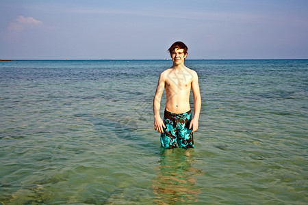 年轻的男孩站在美丽的清海中在美丽而图片