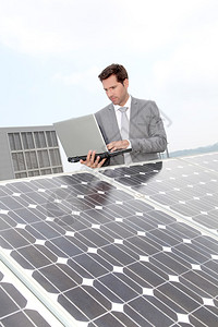 站在太阳能电池板旁的商人图片