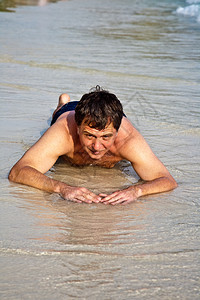 穿泳衣的人躺在沙滩上享受咸水与微小图片
