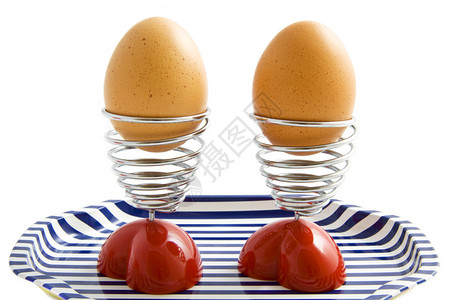 鸡蛋杯中两个蛋放在一个盘子上在白图片