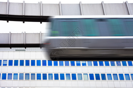 悬挂在高架导轨上的现代公共交通系统轻轨在高大的办公楼立面图片