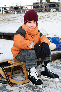 小男孩滑冰后在雪橇上休息图片