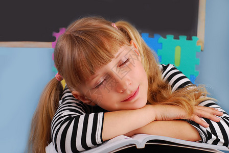疲倦的女学生睡在教室的书上图片