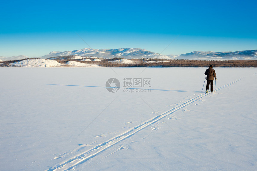 美丽的寒冬日让跨国滑雪者在滑雪图片