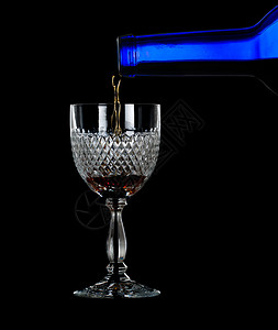 将雪利港或威士忌从蓝酒瓶倒入优雅的切割玻璃杯图片
