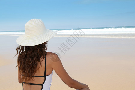 戴着草帽坐在沙滩上的美女图片