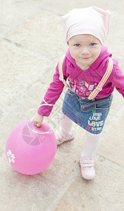 拿着粉红色气球的蹒跚学步的孩子图片