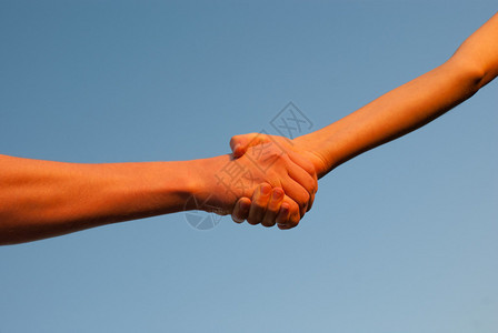 双手在蓝天的映衬下相互握手图片
