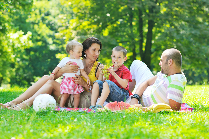 快乐的年轻夫妇和孩子一起在美丽的户外公园玩得图片