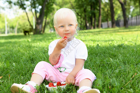 在夏日公园吃草莓的小女孩图片