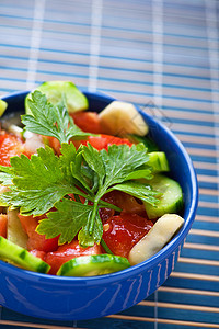 夏季蔬菜沙拉加西红柿和黄瓜盛着青蓝深碗的鹦鹉香煎饼下一个是叉子图片