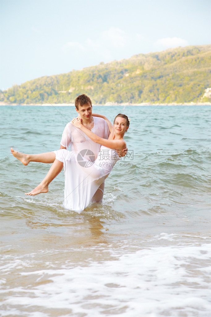 穿着白棉服装的年轻浪漫夫妇在泰国普吉岛海滩的户外肖像图片