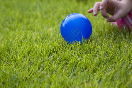 孩子在绿草地上玩蓝色球图片