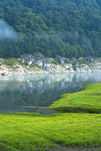 山中的湖绿草和晨雾图片